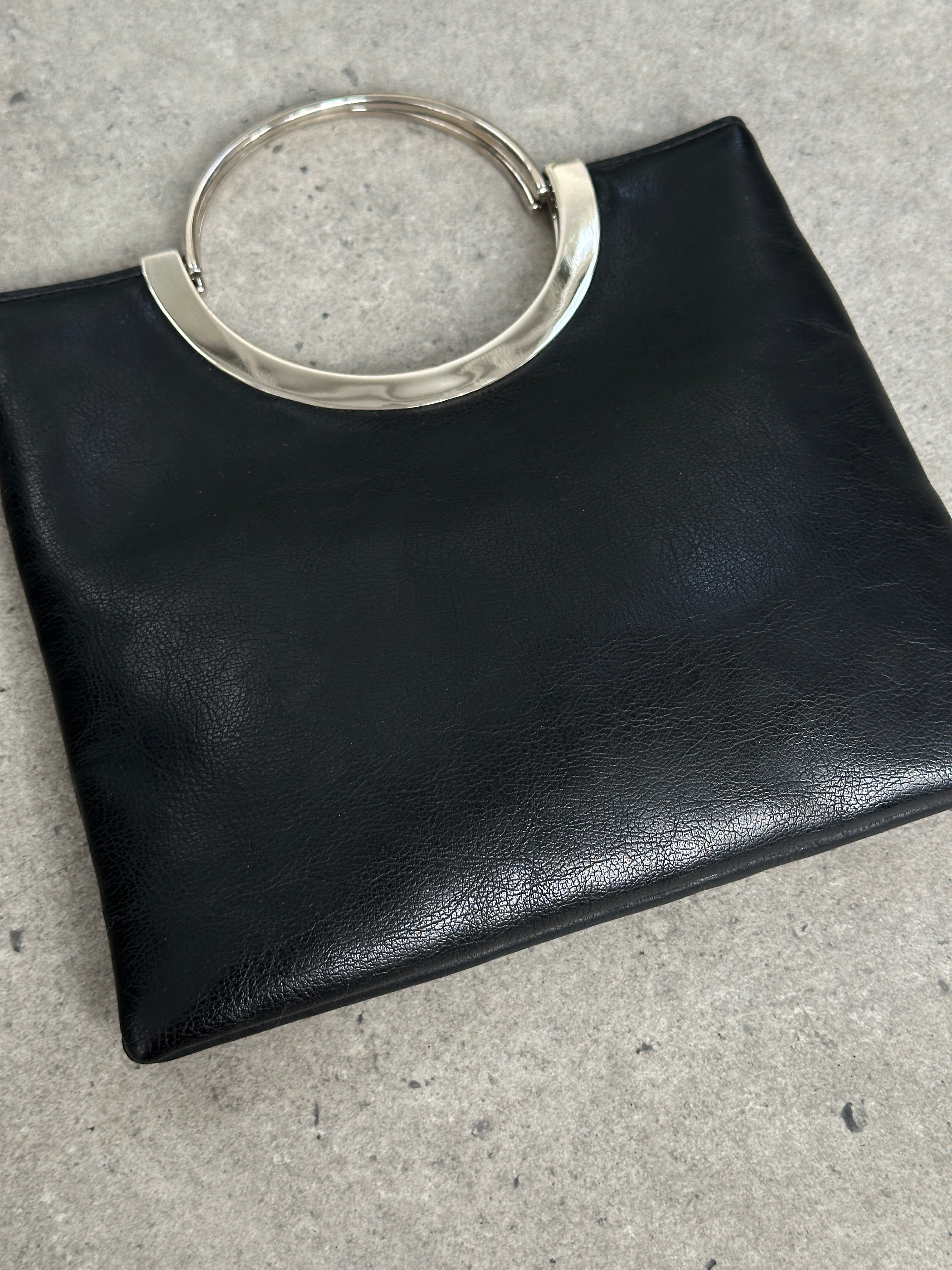 Vintage 1990s minimalist leather bag with sleek design and subtle stitching, featuring a top handle and vintage branding details.