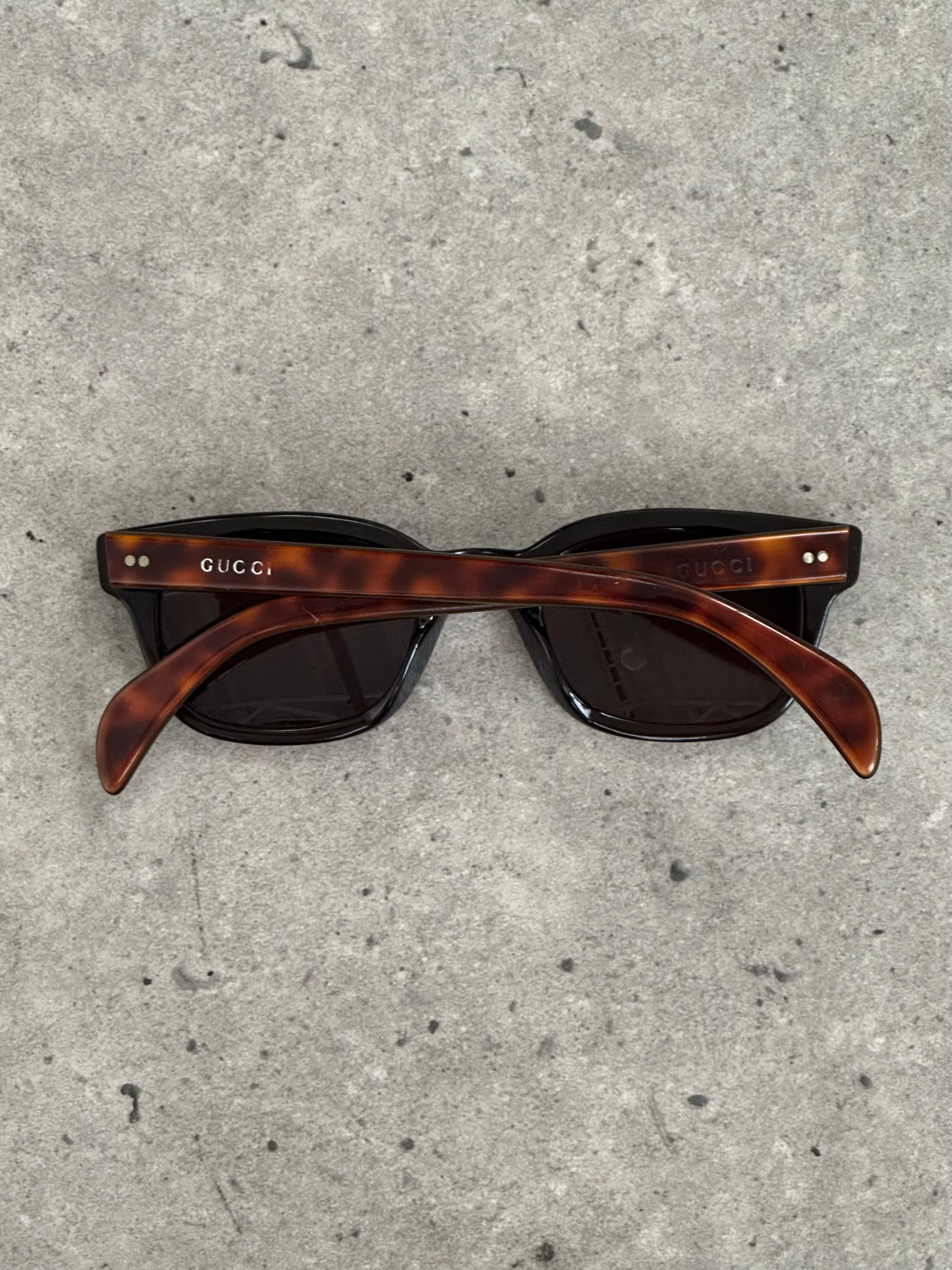 Gucci 2000s Tom Ford tortoiseshell rectangle logo sunglasses with dark lenses and gold accents.