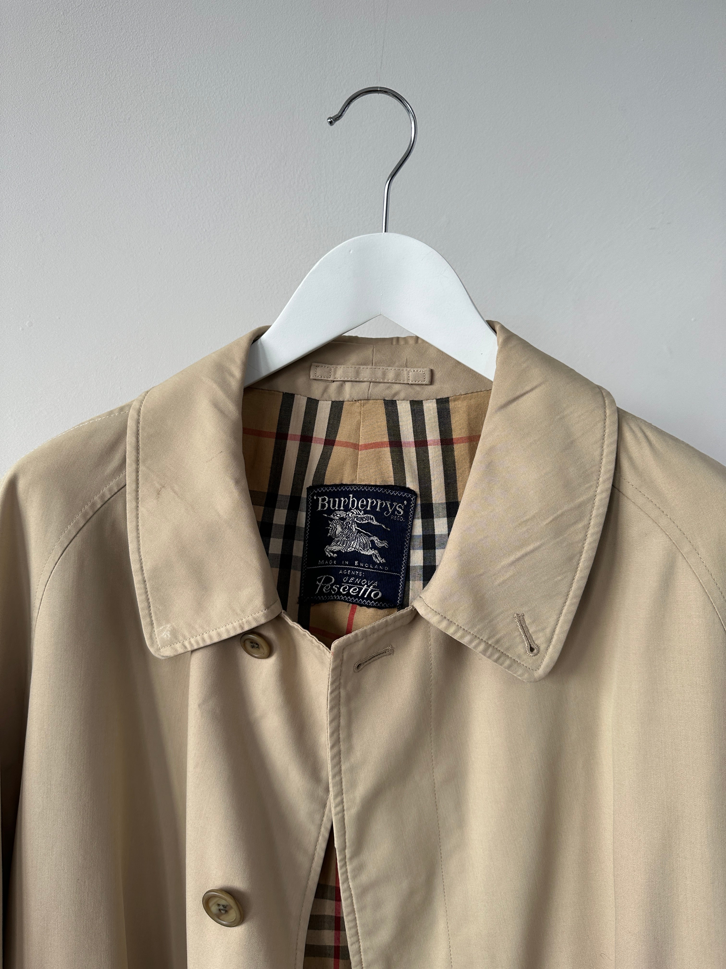 Burberry Nova Check trench coat in size L displayed on a hanger, featuring classic check pattern and tailored design.
