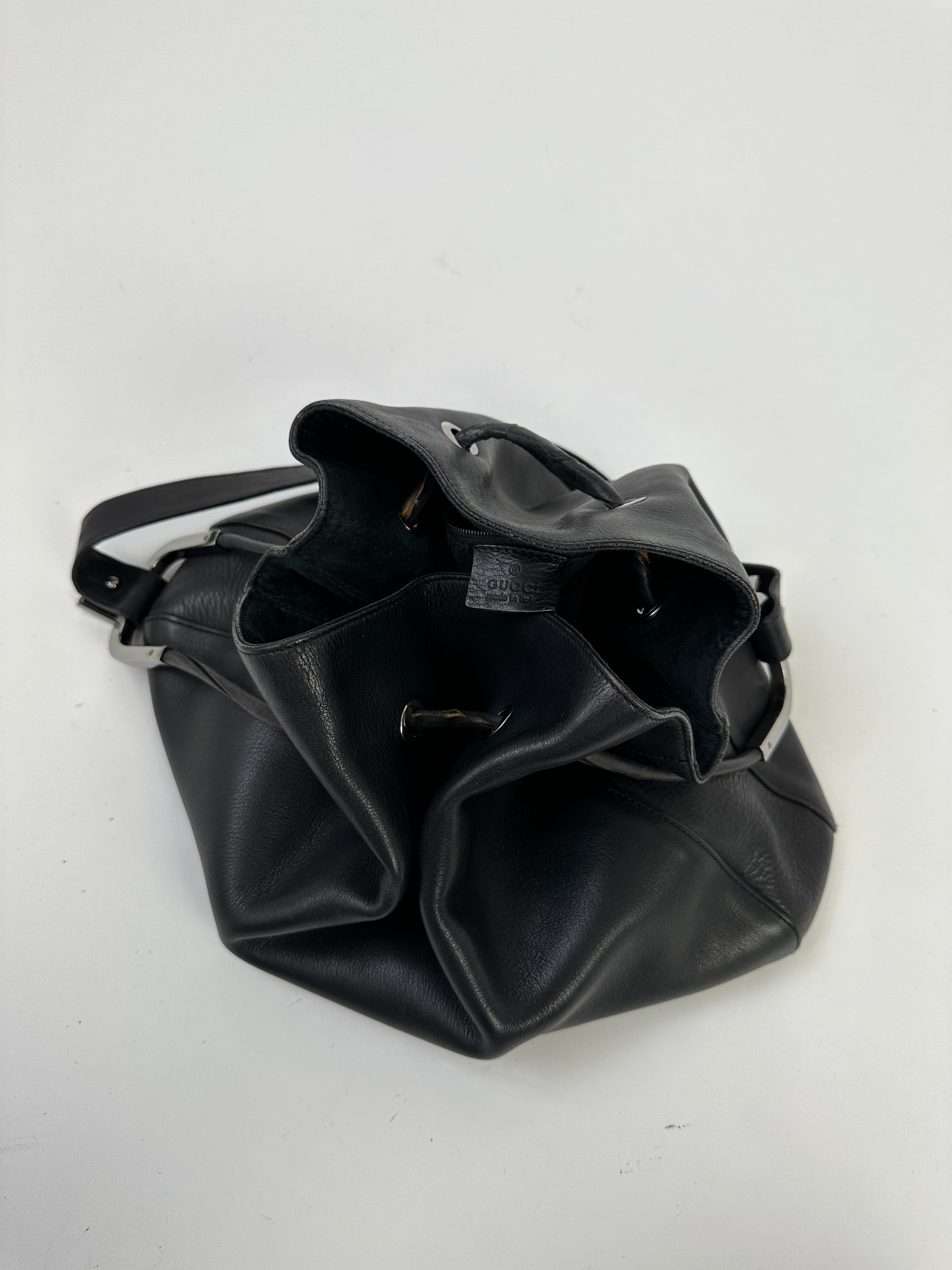 Gucci leather bucket bag with adjustable strap, featuring smooth brown leather and gold-tone hardware.