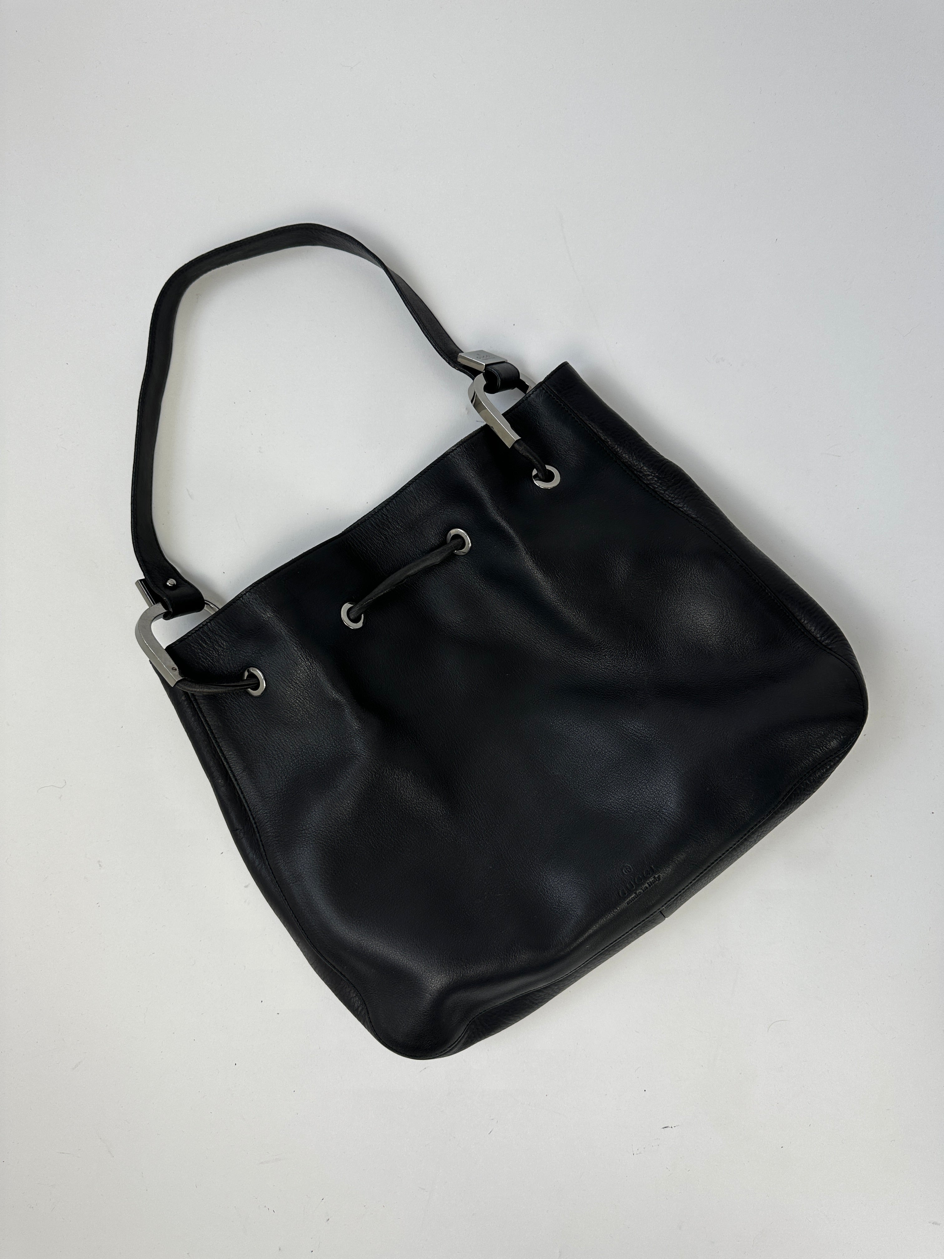 Gucci leather bucket bag with adjustable strap, featuring smooth finish and minimalist design for stylish everyday use.