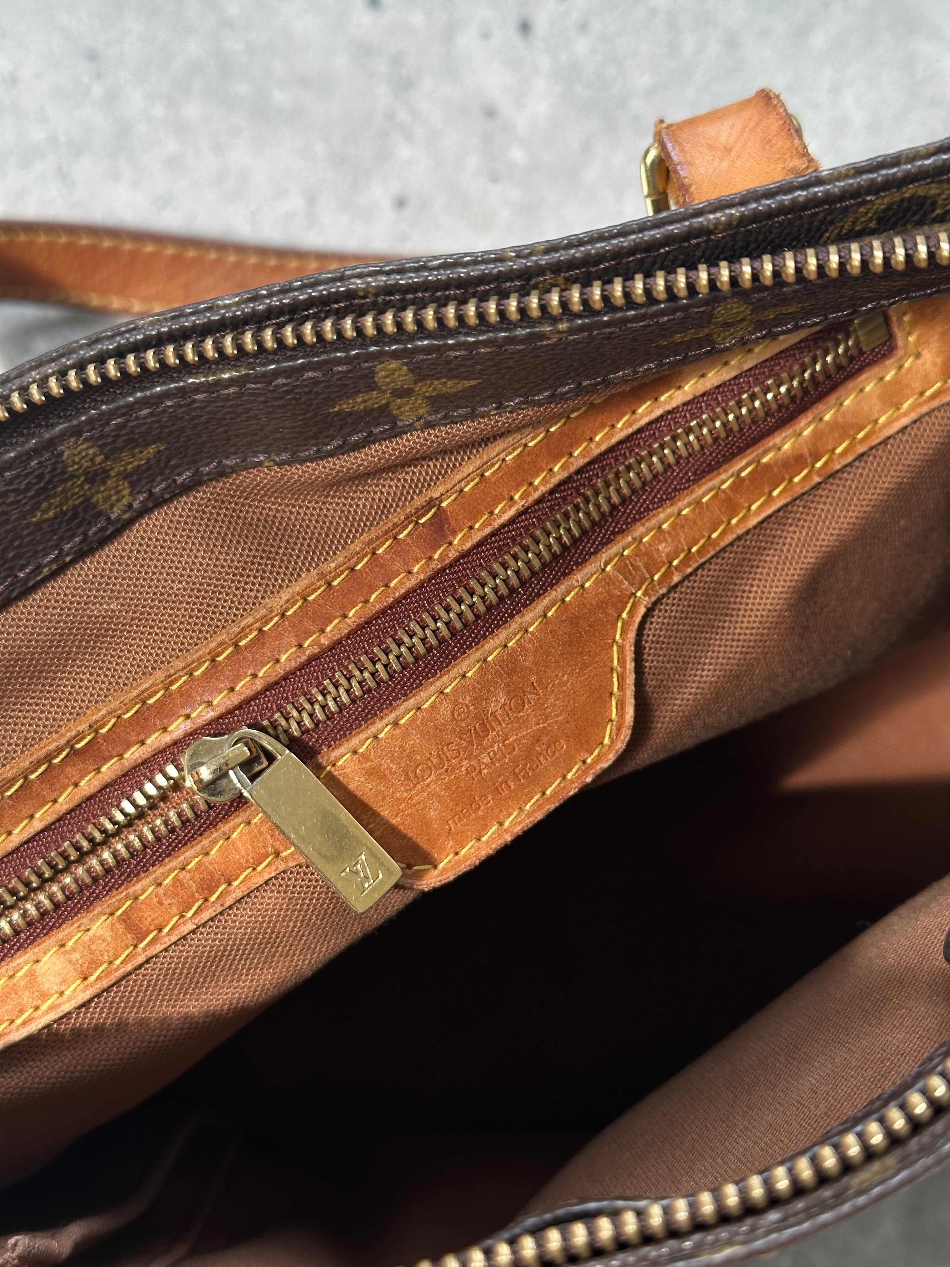 Louis Vuitton 2002 Cabas Mezzo Monogram shoulder bag with leather handles and monogram canvas, displayed on a flat surface.