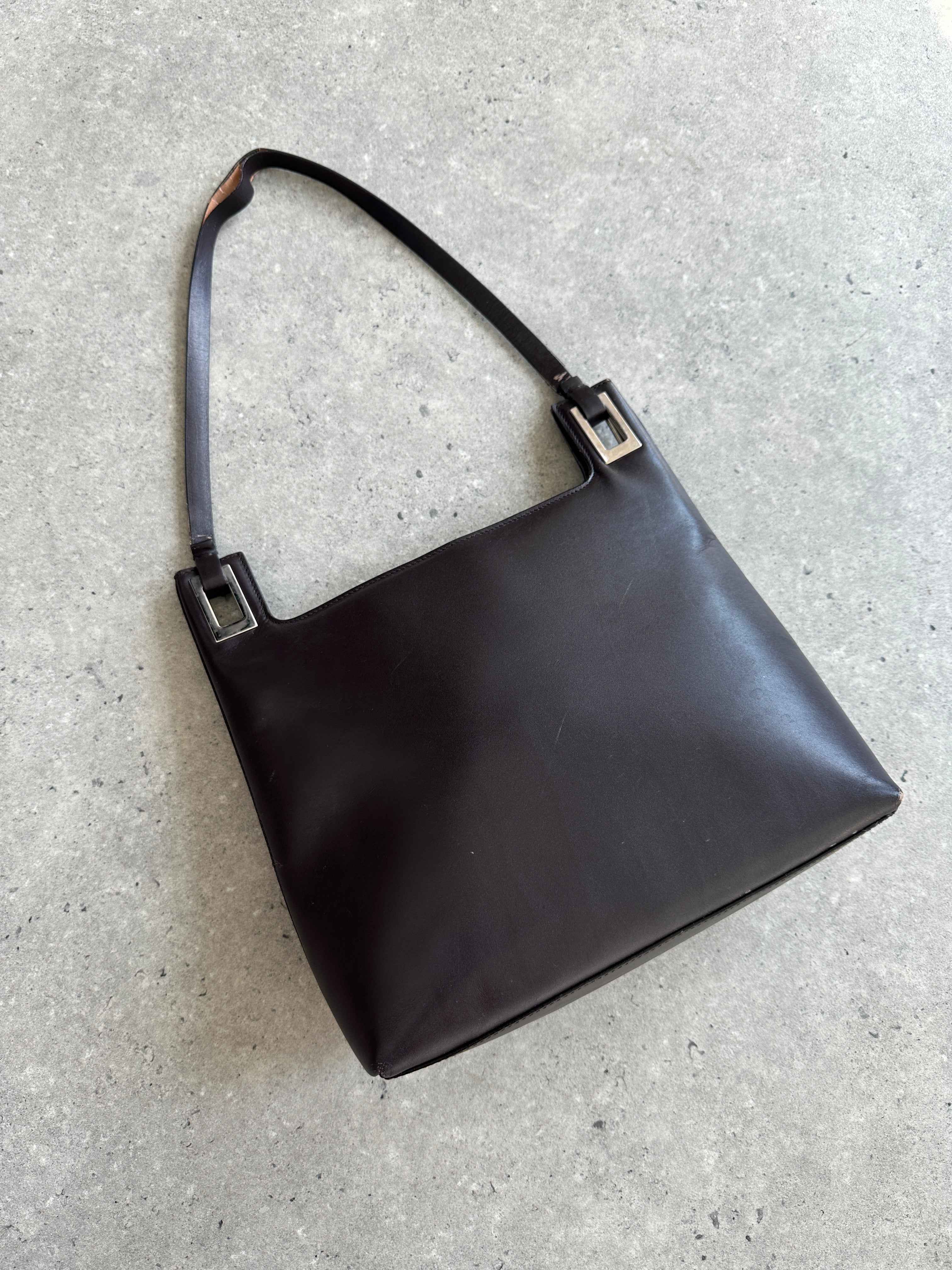 Gucci leather shoulder bag featuring a sleek design, with a top handle and adjustable strap, on a white background.