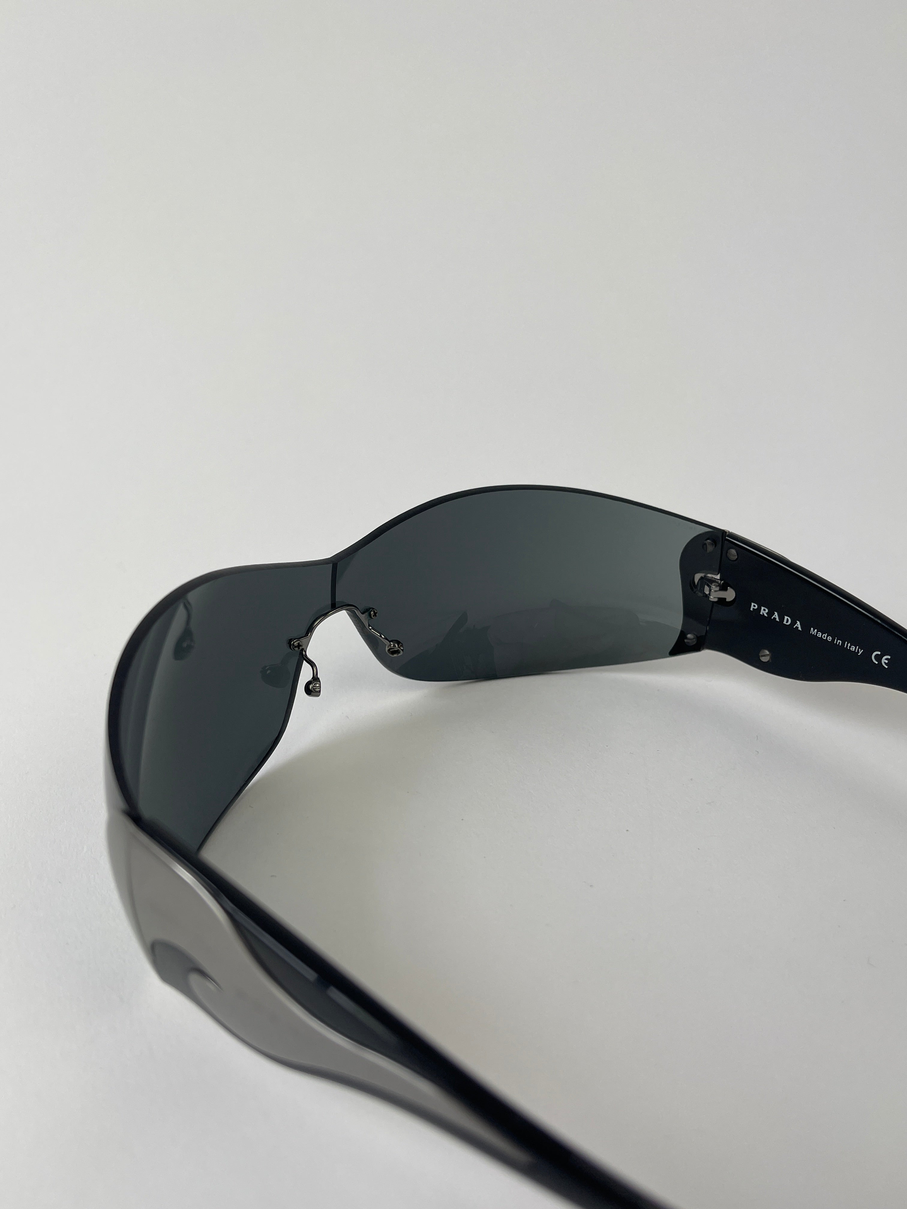 Prada Flame Rimless Wrap Sunglasses with sleek, modern design and clear lenses, featuring a stylish rimless frame.
