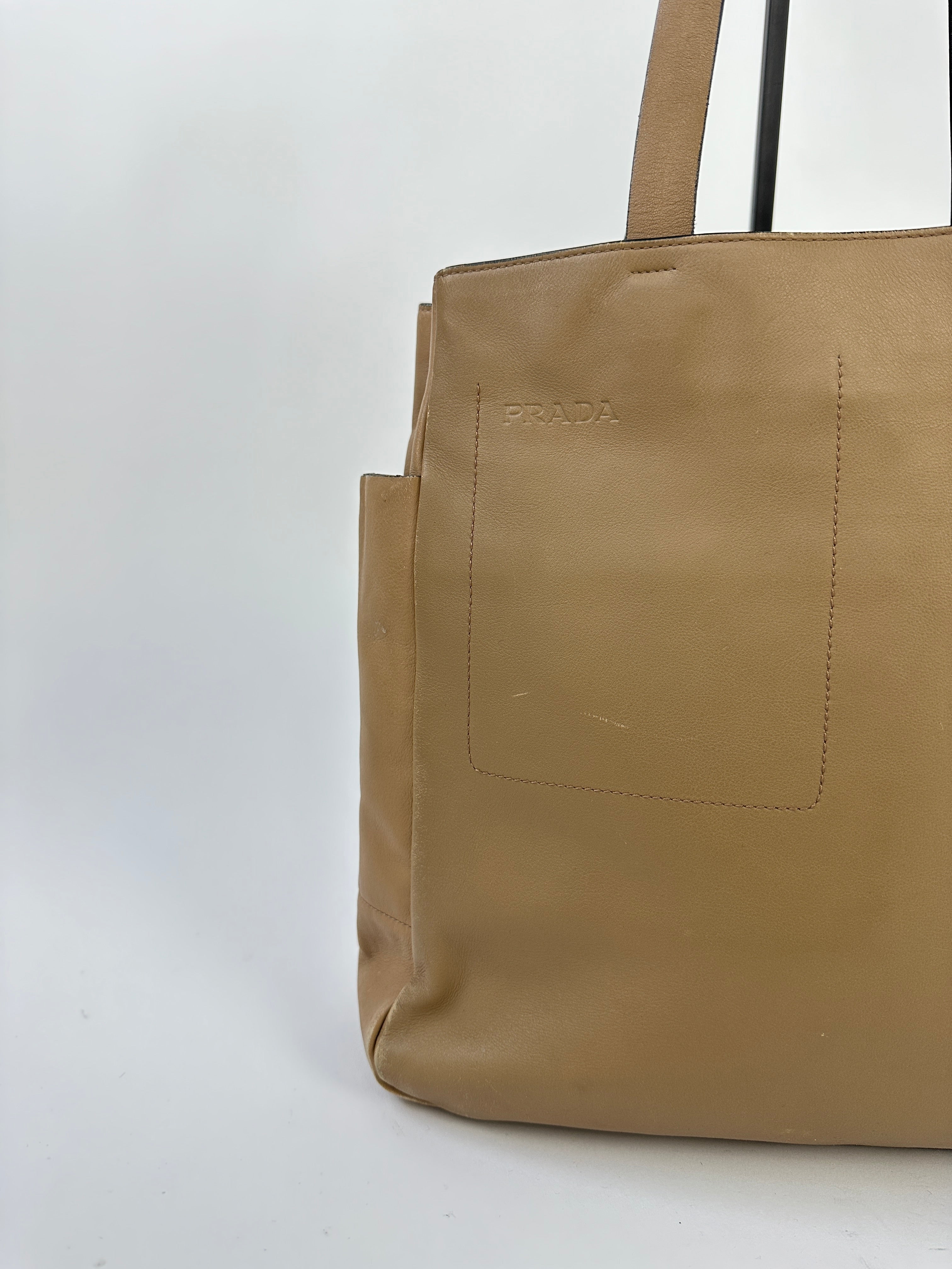 Prada contrast leather tote bag with sturdy handles and sleek design, featuring two-tone leather panels and spacious interior.