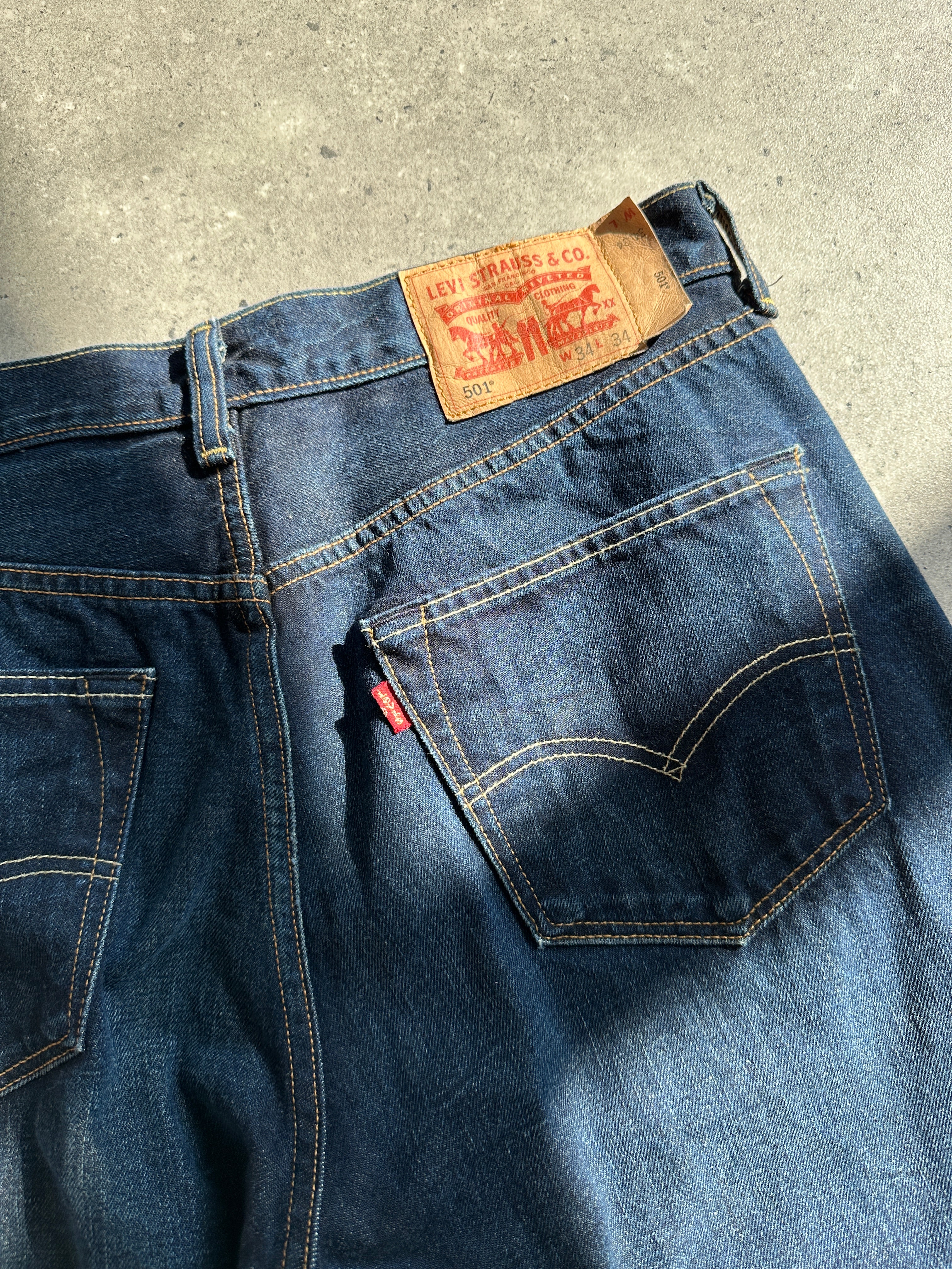 Levi’s 501 dark wash denim jeans with straight leg fit, showing the classic five-pocket design and Levi’s branding.