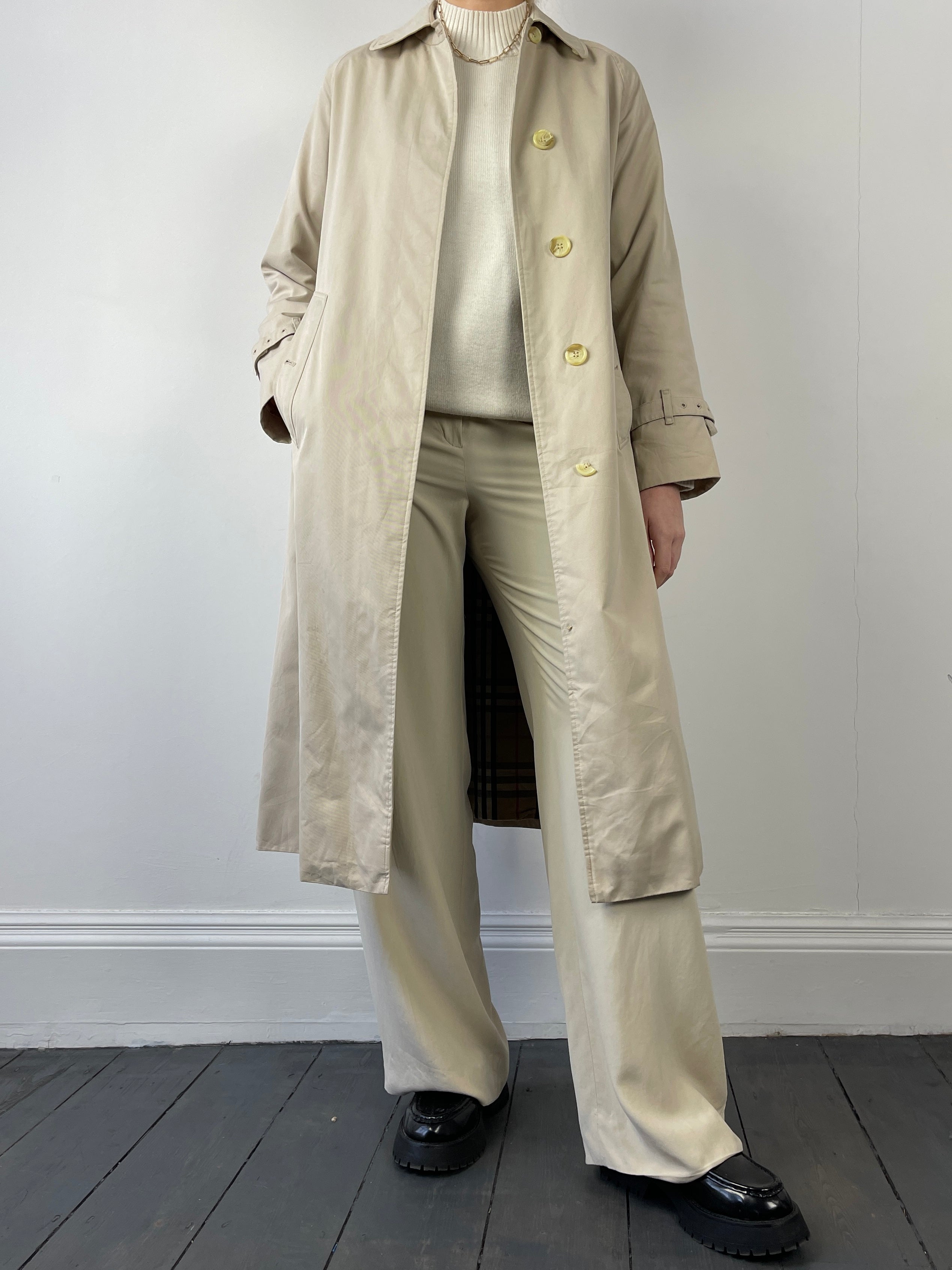 Beige Burberry trench coat displayed on a hanger, showcasing classic design and elegant style.