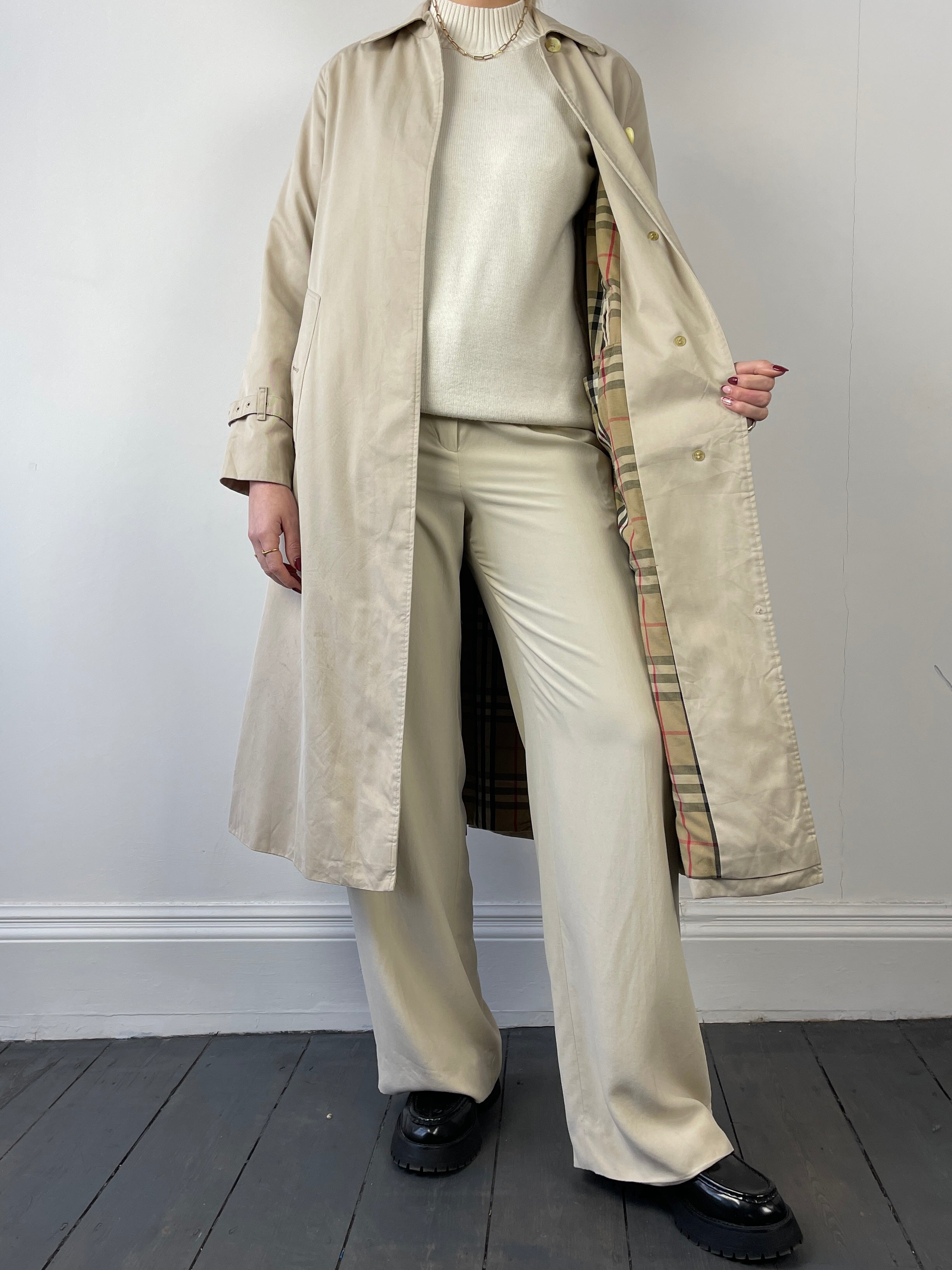 Beige Burberry trench coat for women, featuring classic double-breasted design and belted waist.
