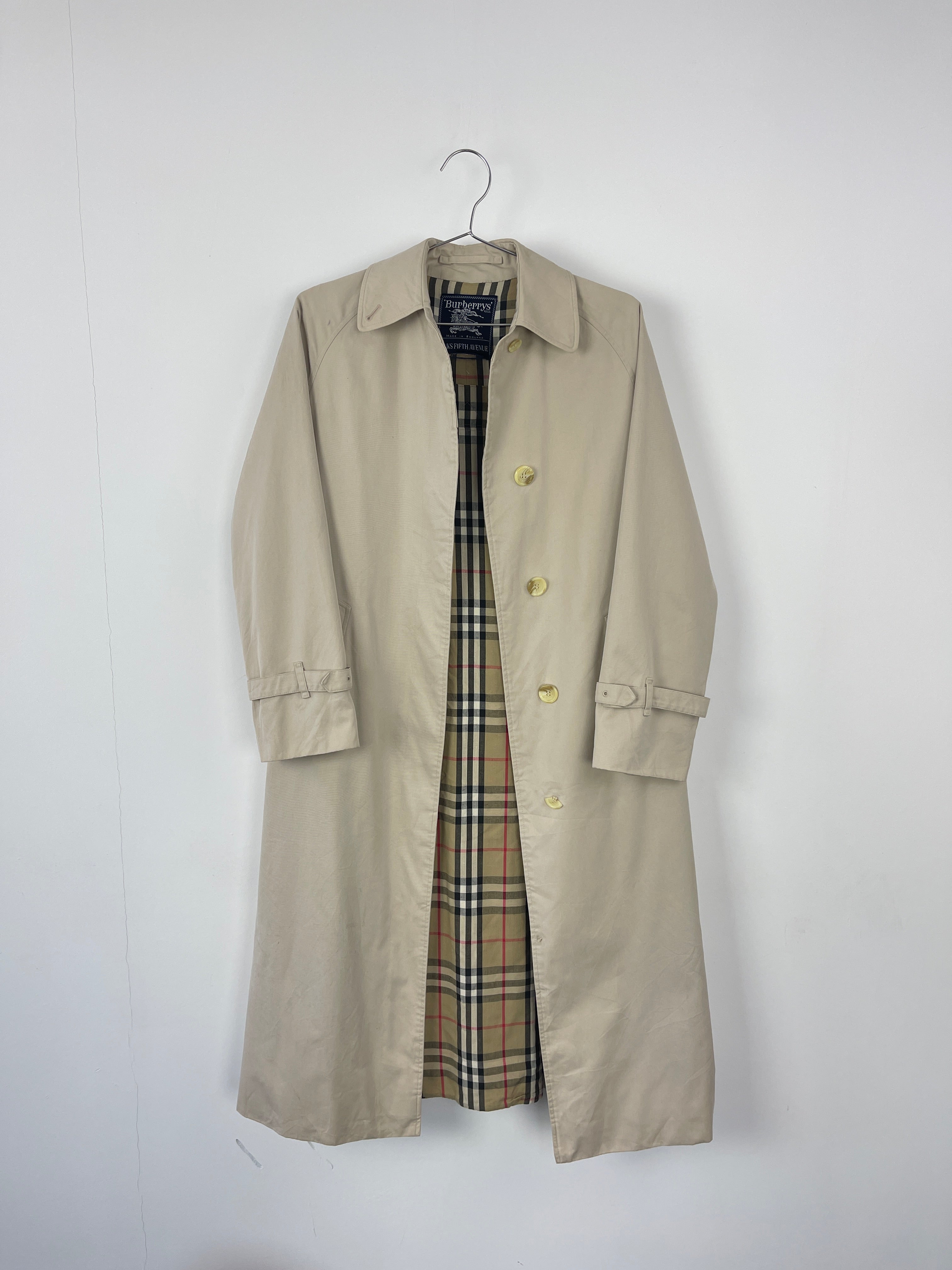 Beige Burberry trench coat displayed on a hanger, showcasing classic double-breasted design and belted waist.