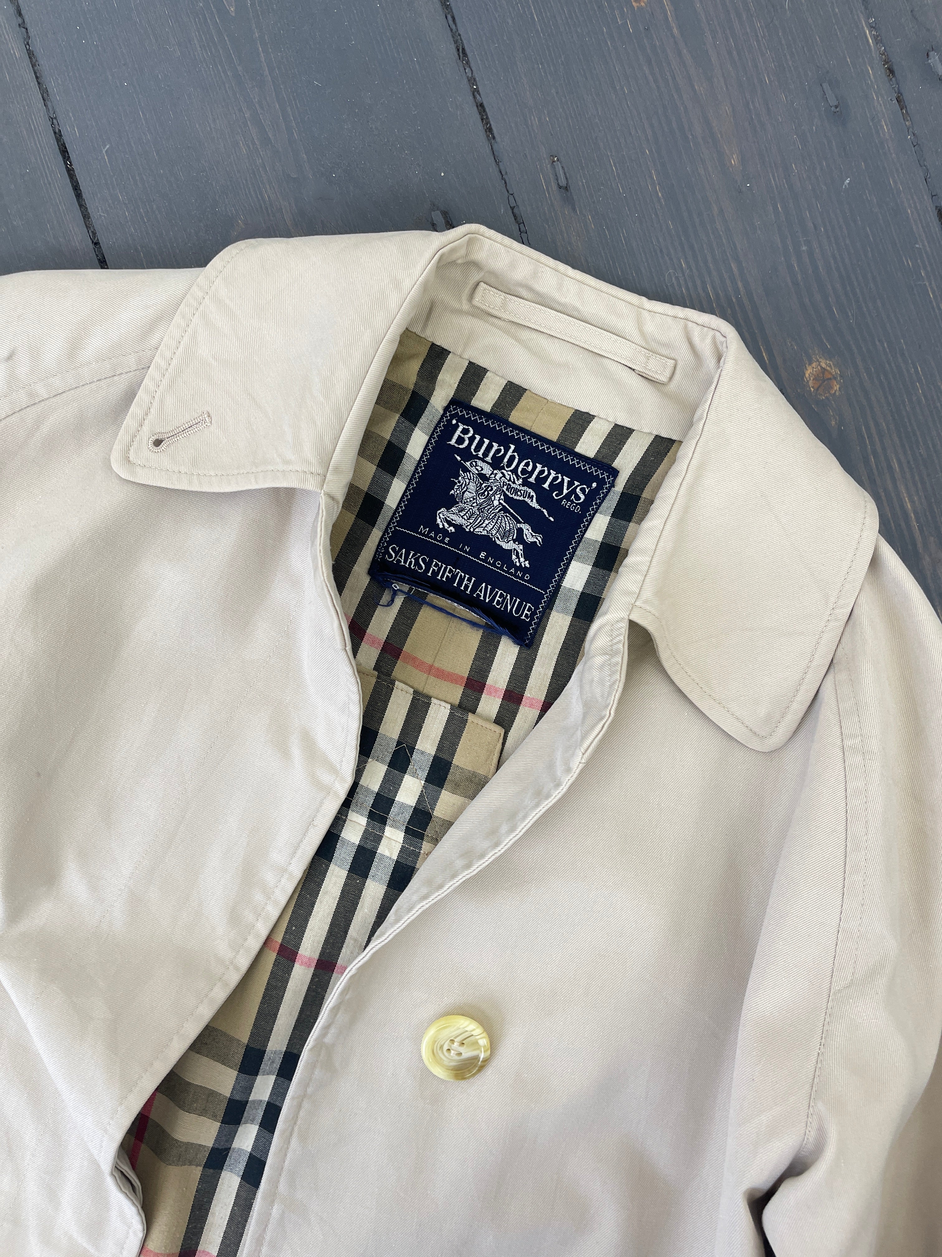 Beige Burberry trench coat for women, showcasing classic double-breasted design and signature check lining.