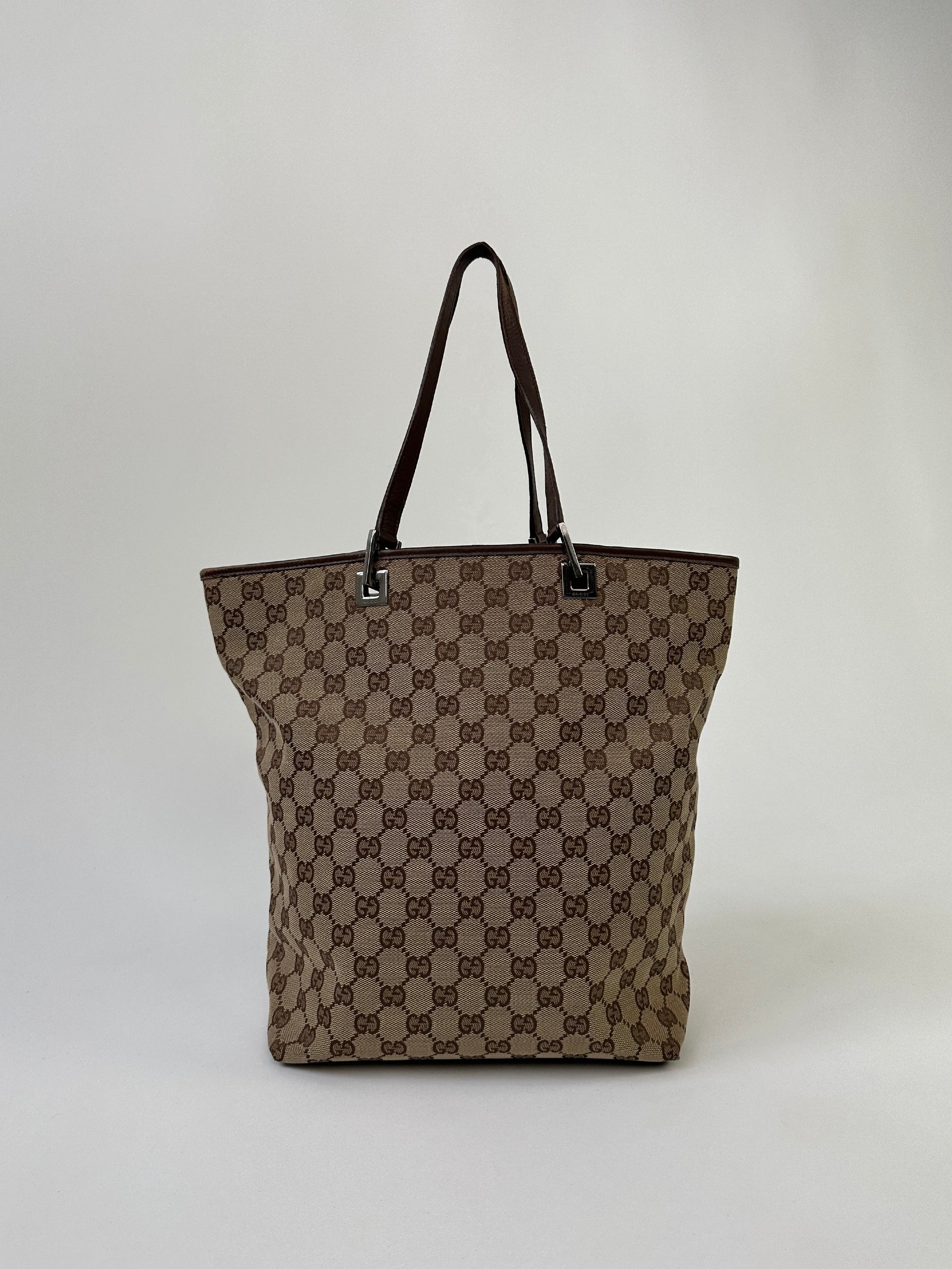 Gucci Monogram GG bucket tote bag with leather trim and adjustable shoulder strap, featuring the signature monogram pattern.