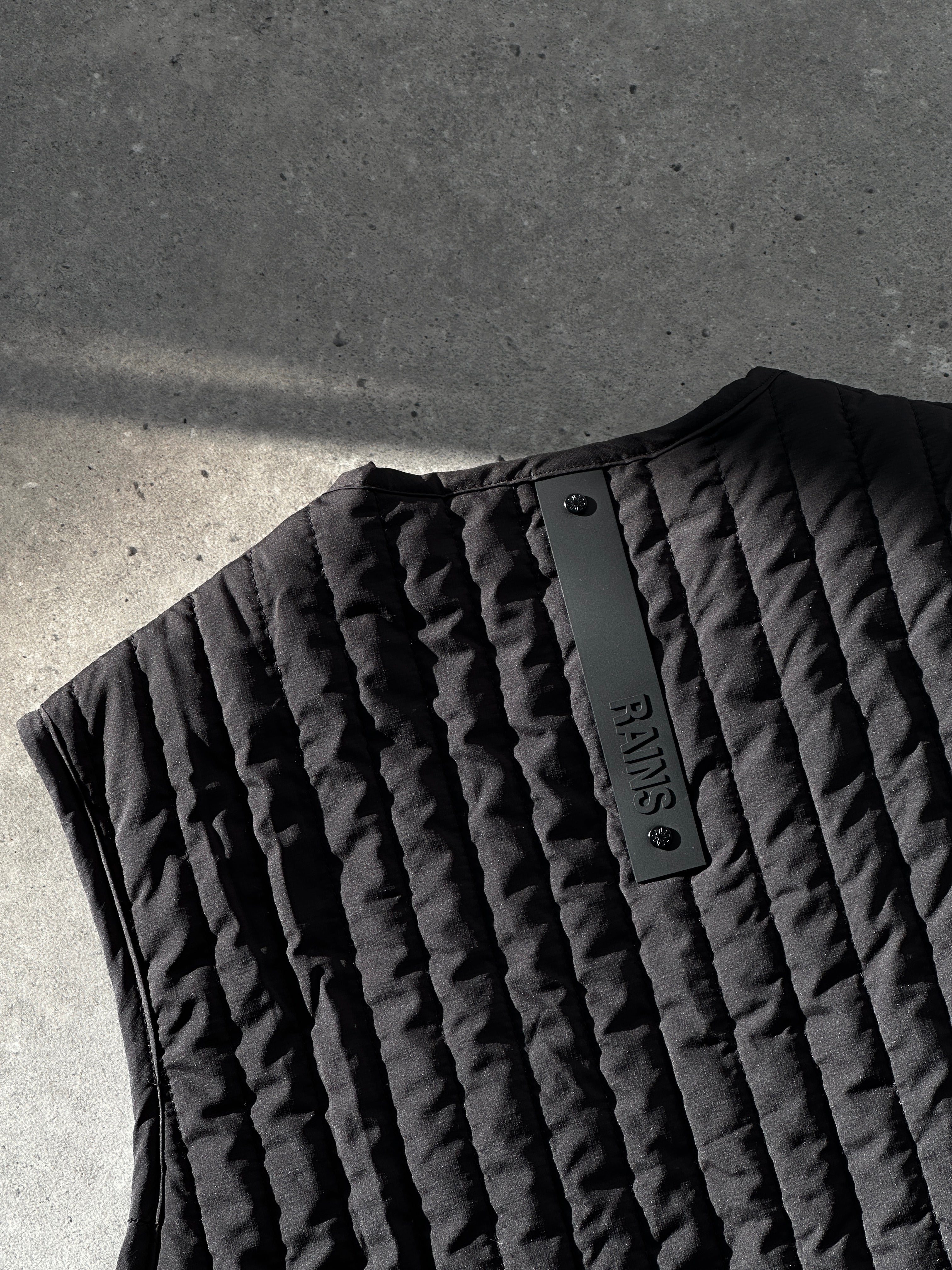 Rains waterproof zip-up liner vest in black, featuring a high collar and sleek design, lightweight and suitable for layering.