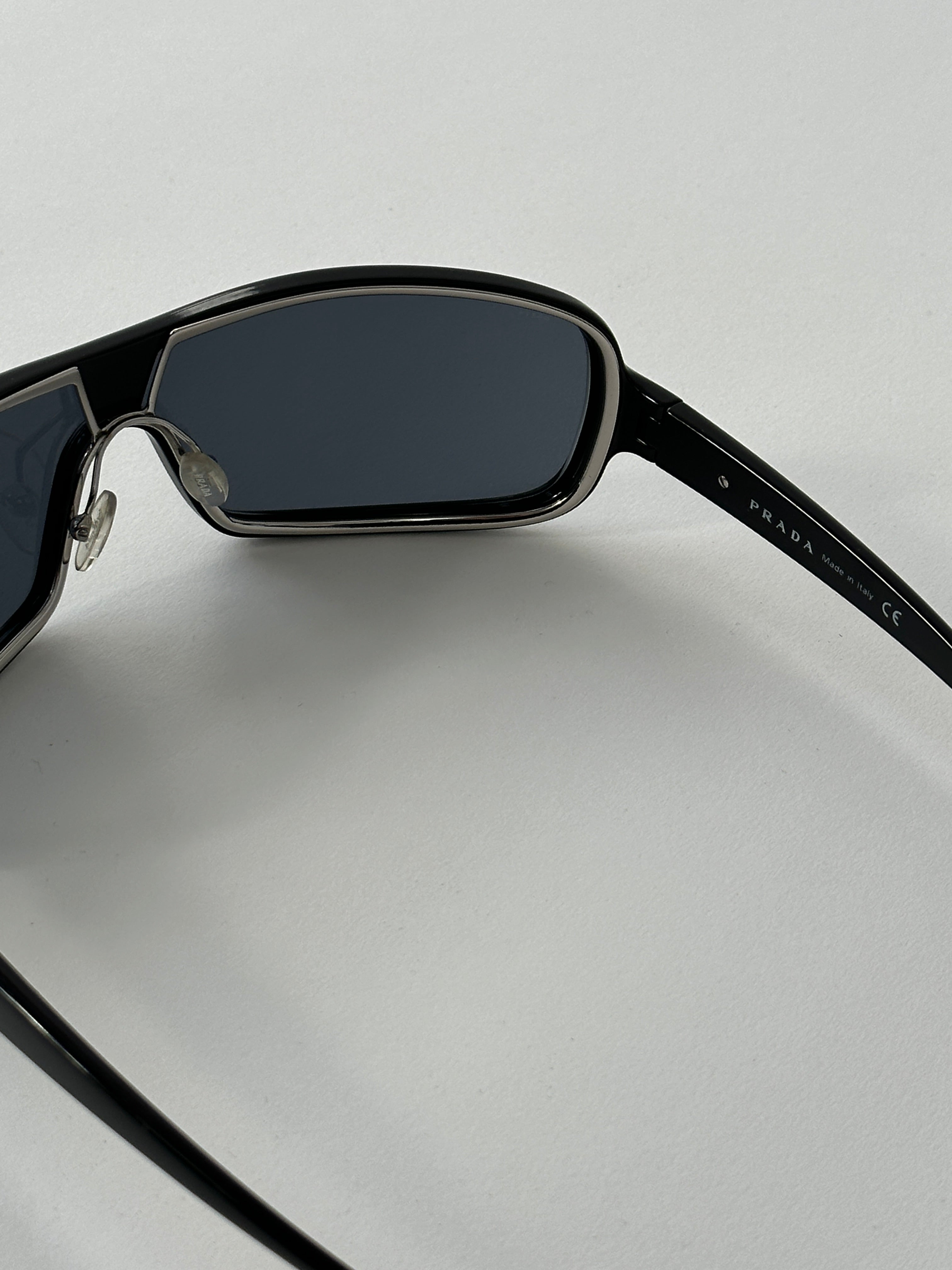 Prada 2000s Shield Sunglasses with bold black frames and dark tinted lenses, stylishly designed for a modern look.