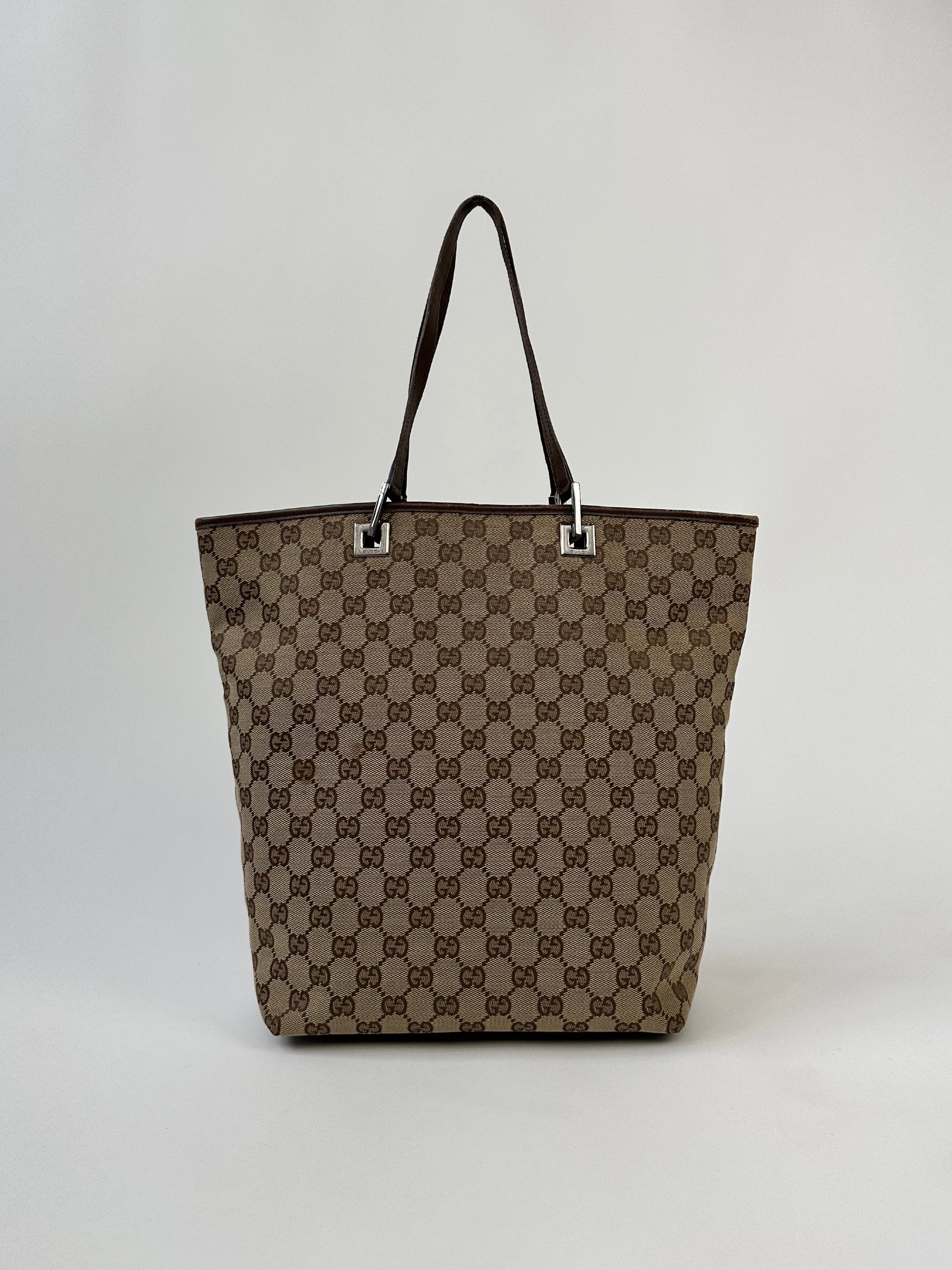 Gucci Monogram GG bucket tote bag with leather trim and adjustable shoulder strap, featuring iconic monogram pattern and spacious interior.