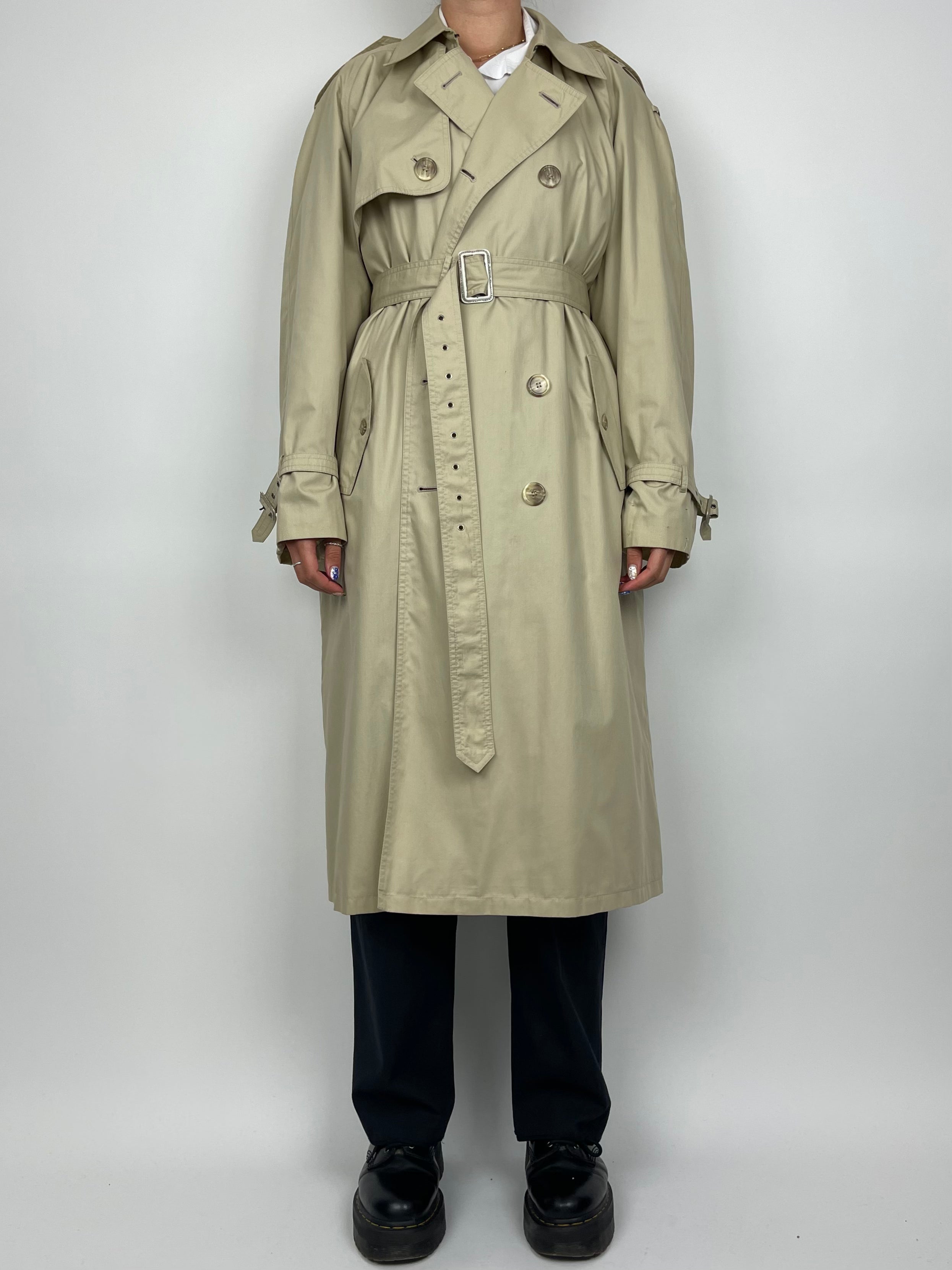 Yves Saint Laurent cotton trench coat hanging on a wooden hanger, showcasing classic beige color and tailored fit.
