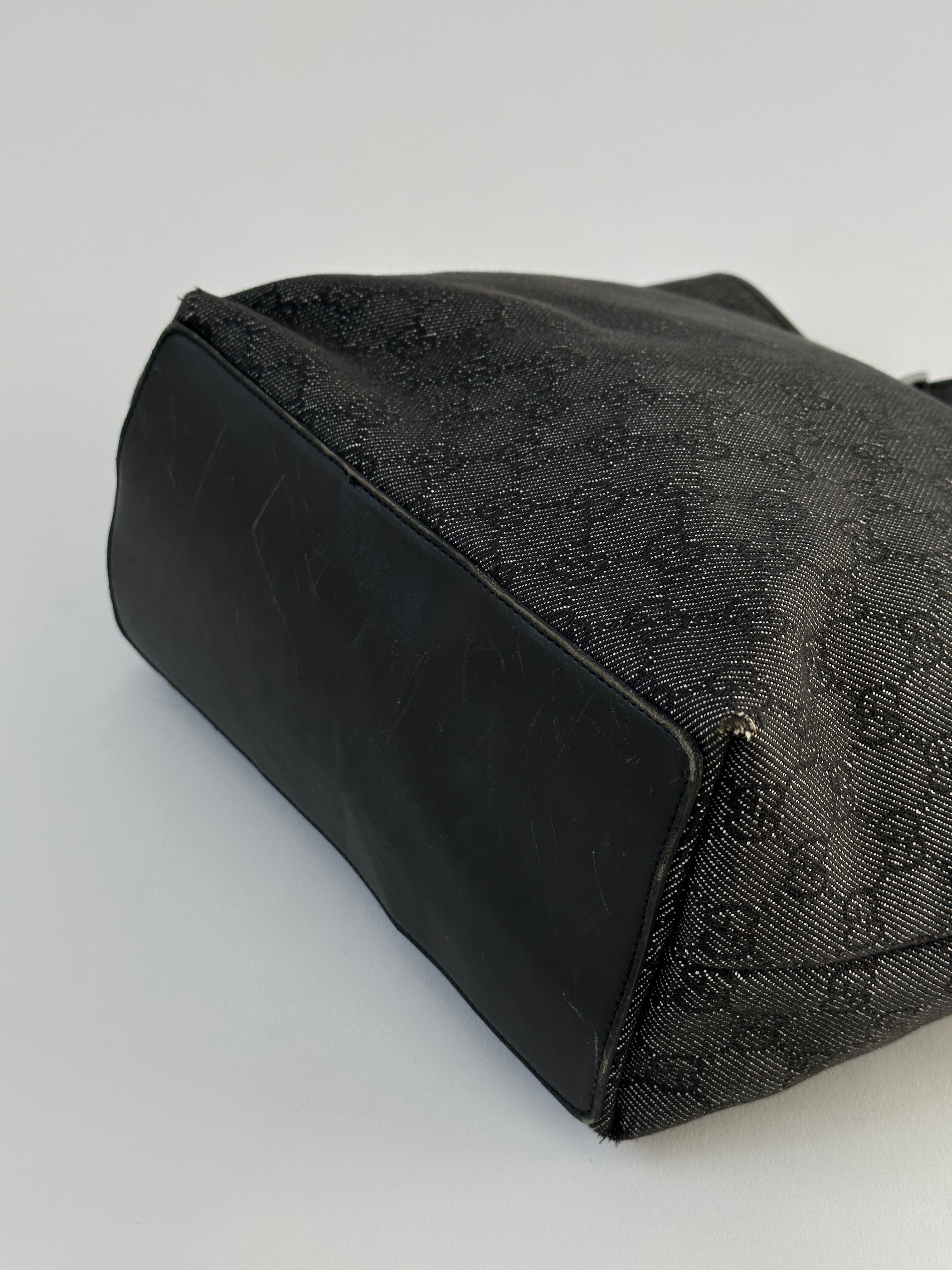 Gucci Monogram GG bucket tote bag with leather trim and adjustable shoulder strap, featuring signature monogram pattern.
