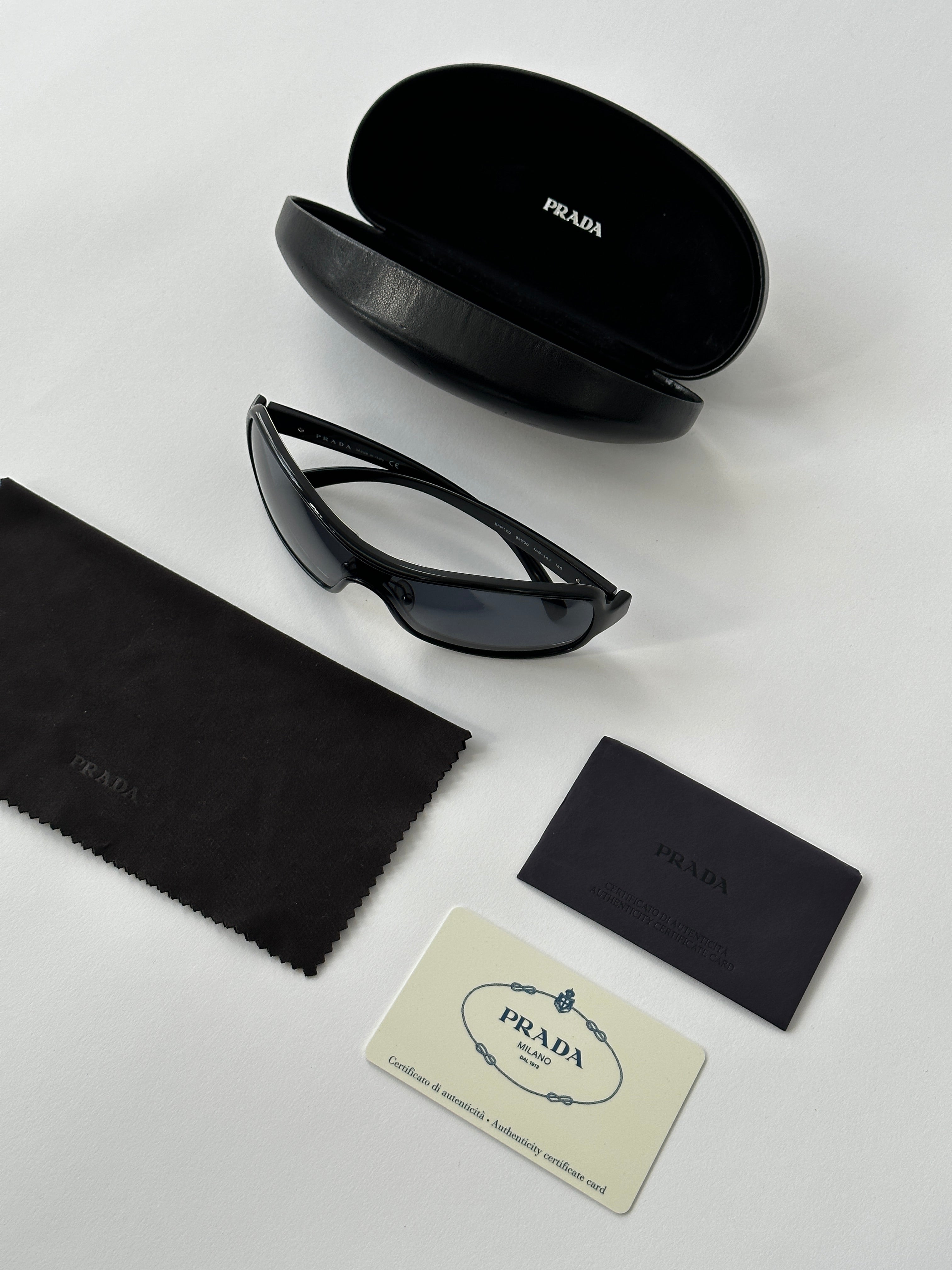 Prada 2000s Shield Sunglasses with black frame and dark lenses, featuring a sleek, modern design and distinctive shield shape.