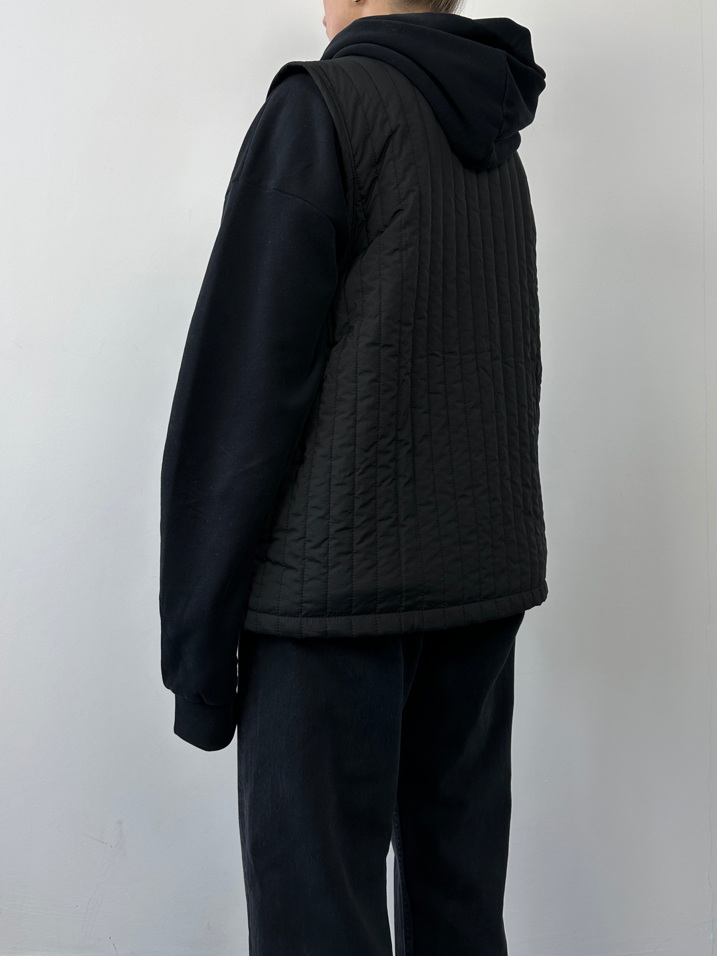 Rains waterproof zip-up liner vest, lightweight gilet in black, showing front view with high collar and smooth fabric finish.