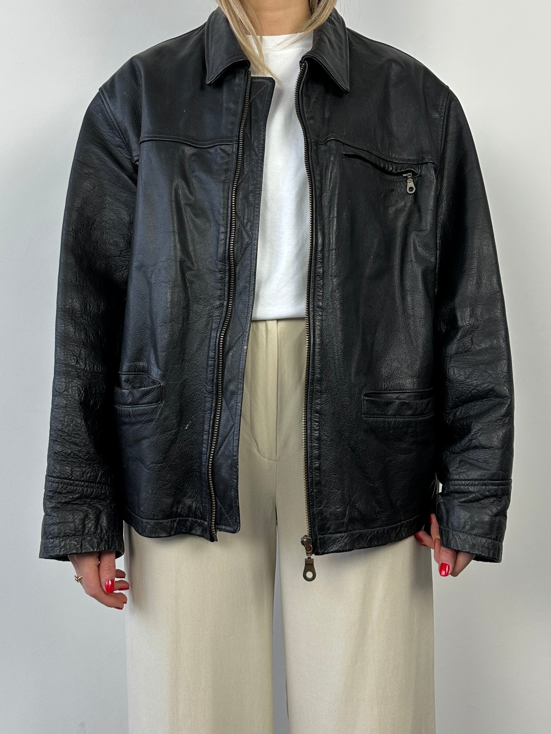 Black vintage boxy leather jacket by Vintage, shown on a hanger with a textured leather finish and classic collar style.