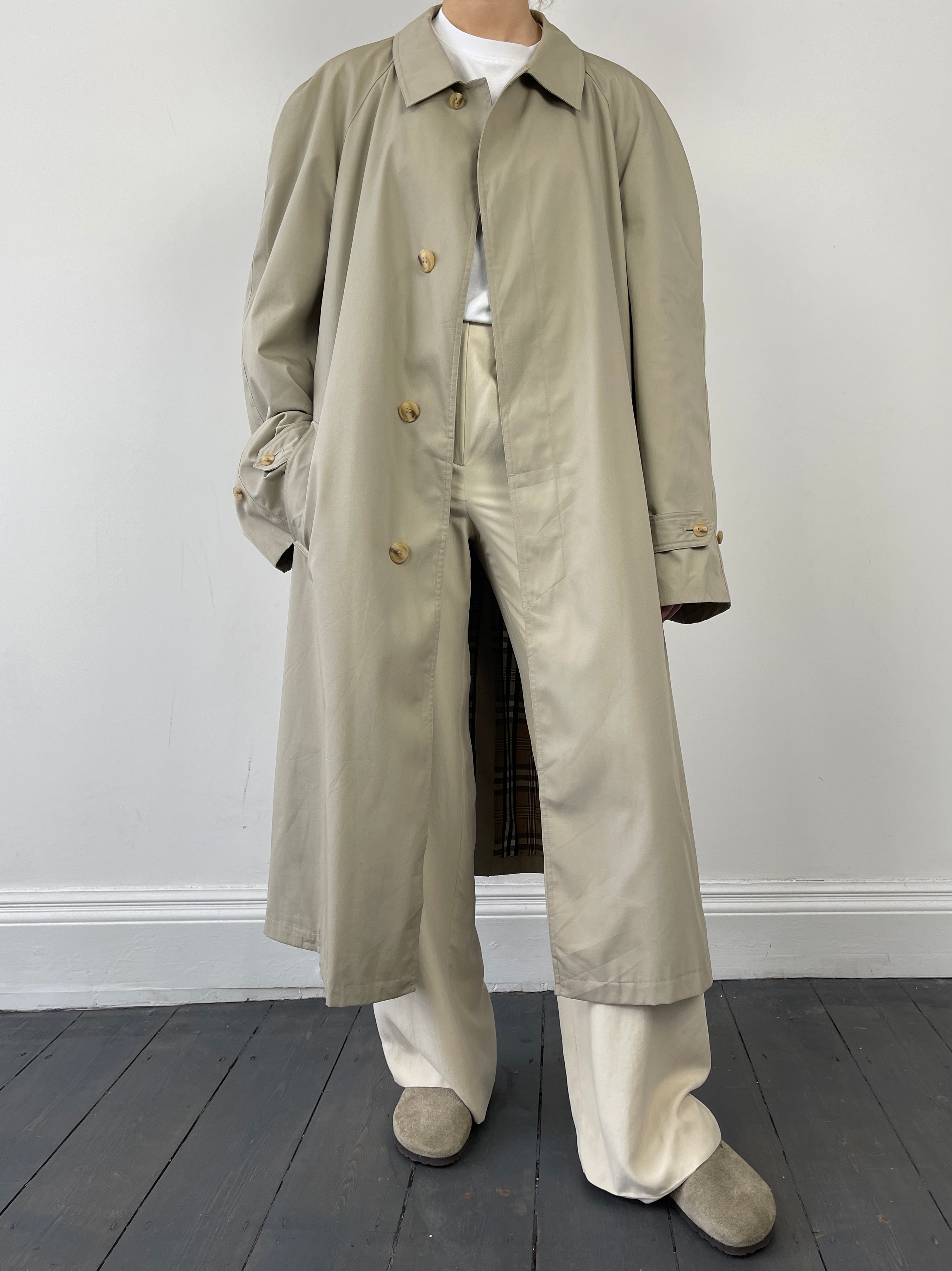 Beige vintage cotton belted trench coat with classic design, large fit, and timeless style, displayed on a hanger.