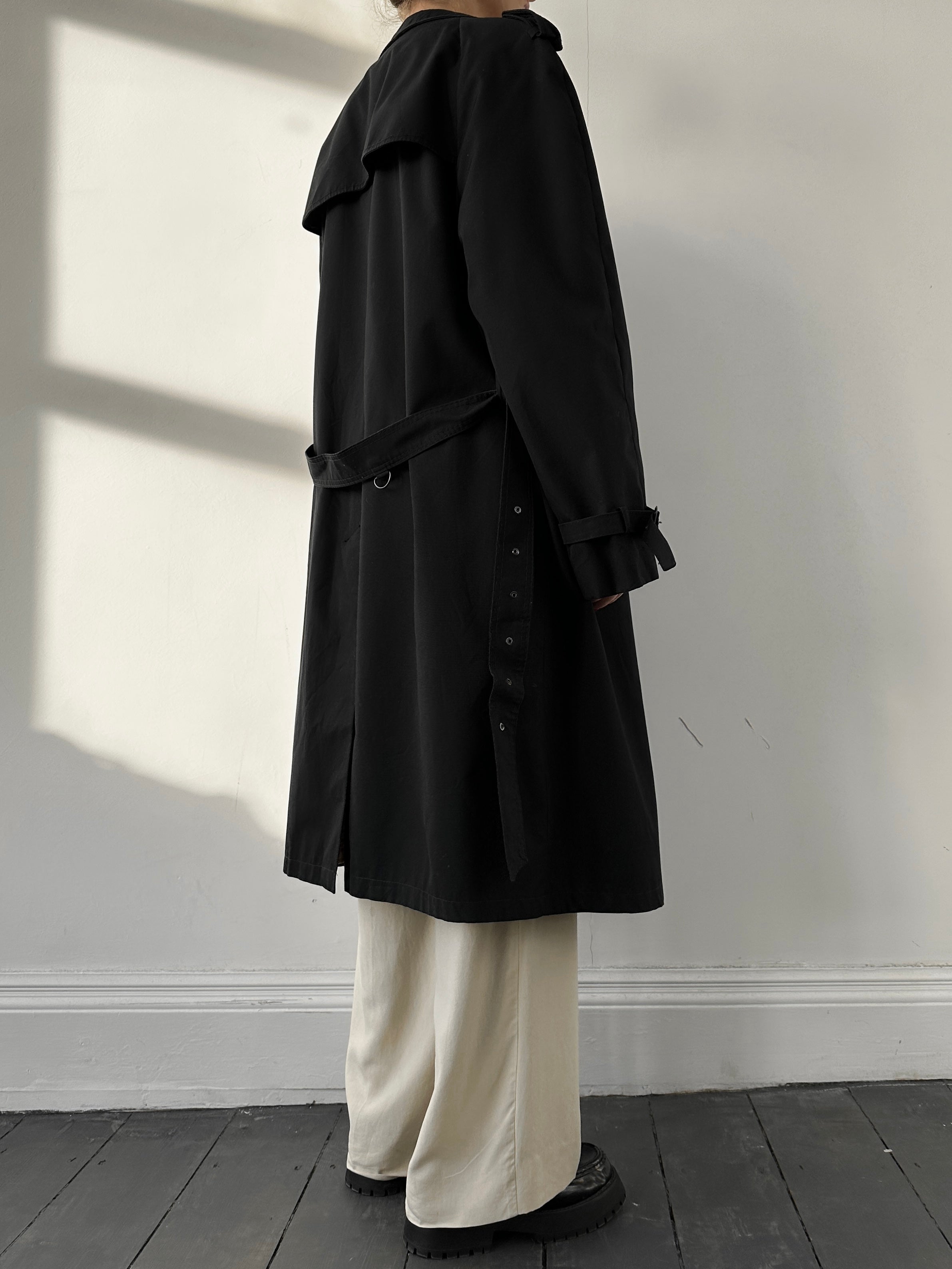 Black Vintage belted cotton trench coat with large lapels and classic design, displayed hanging on a mannequin.