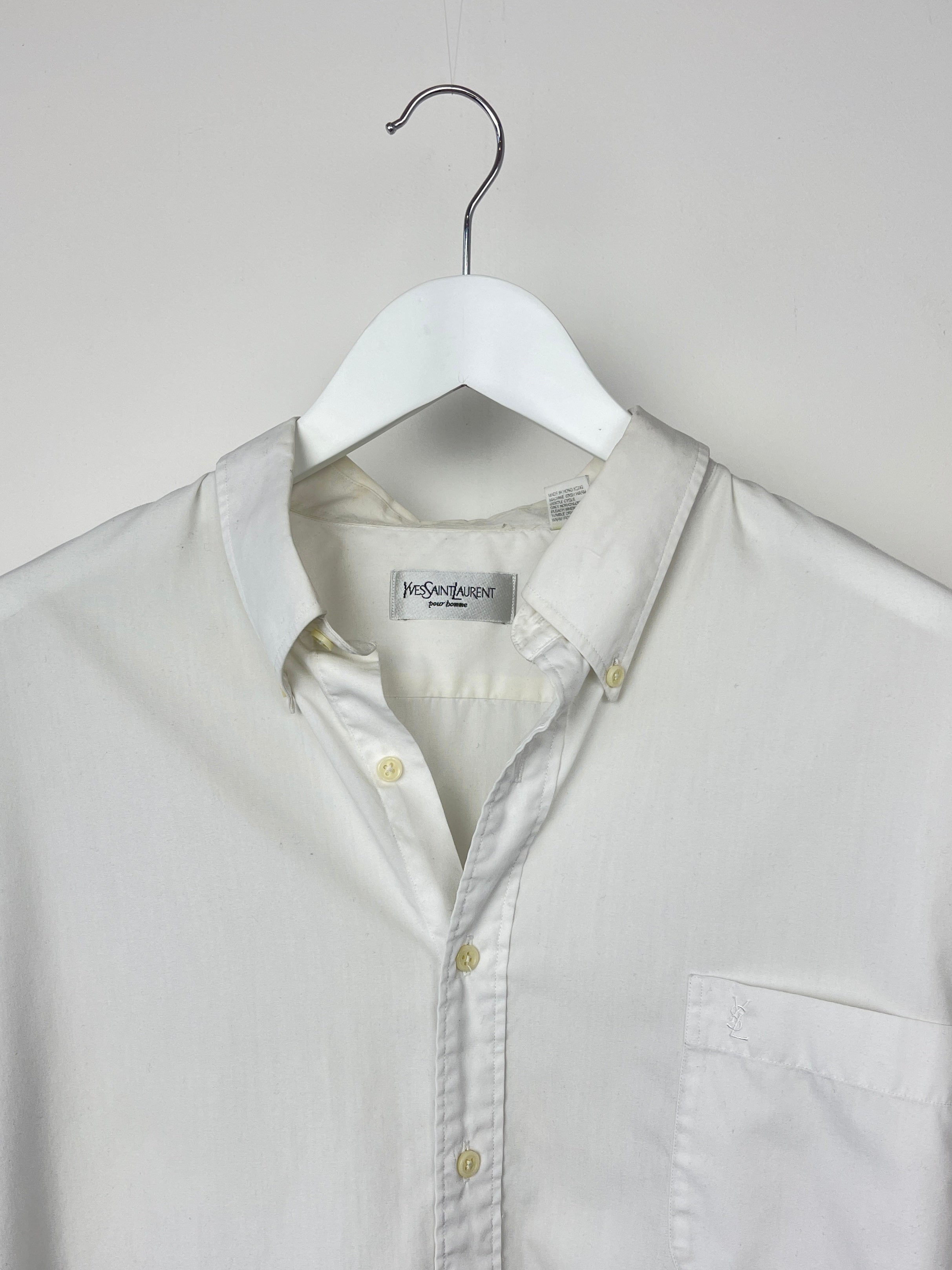 White Yves Saint Laurent cotton shirt with classic collar and long sleeves, displayed on a hanger.